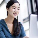 A woman smiling while using her computer.