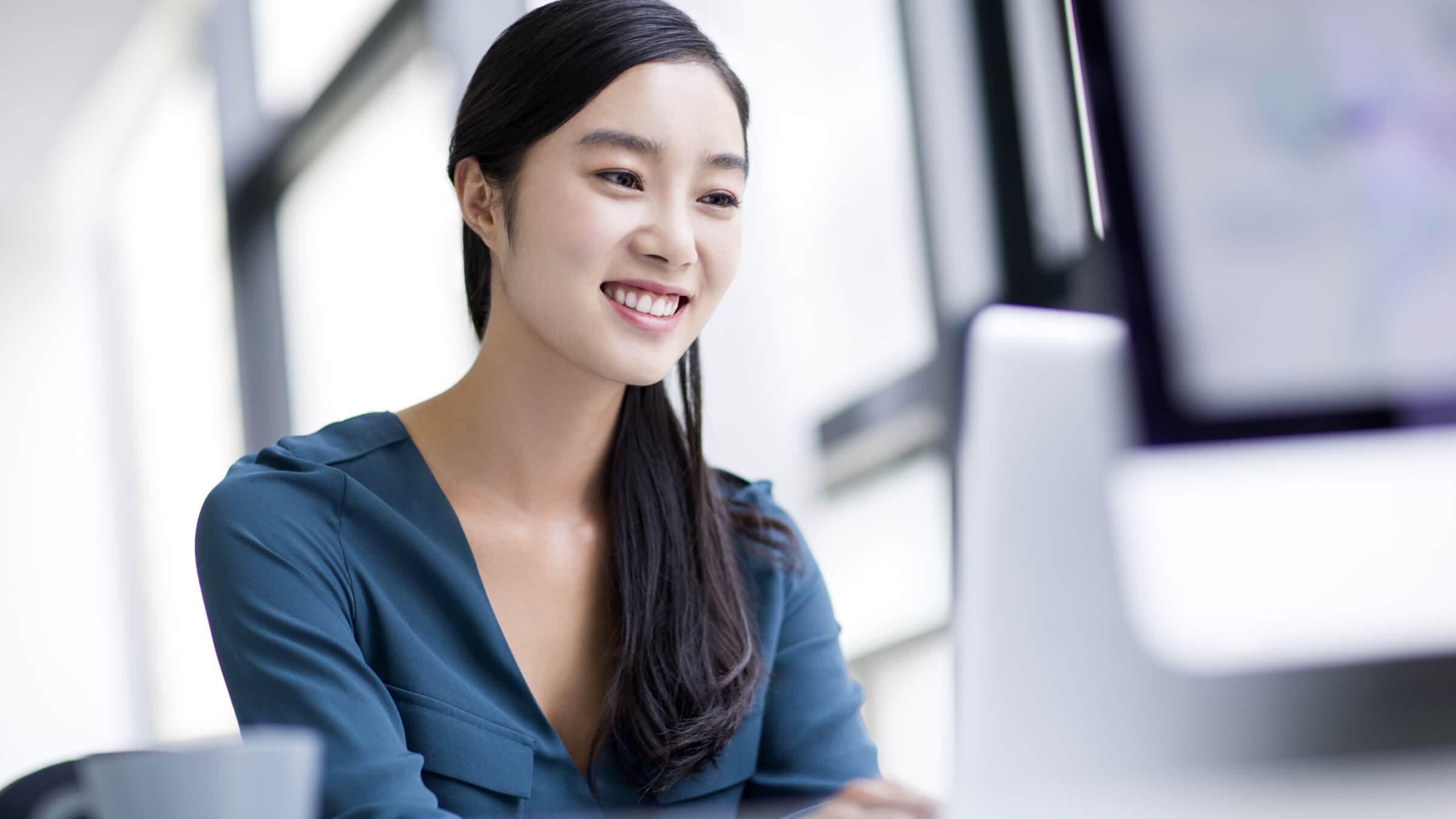 A woman smiling while using her computer.