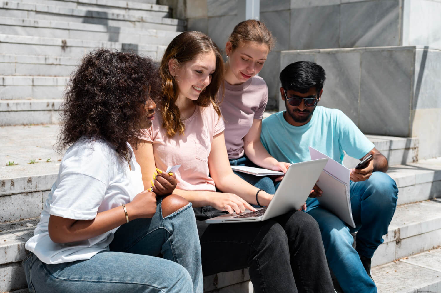 Five people sitting on the floor with laptops, engaged in work or study.