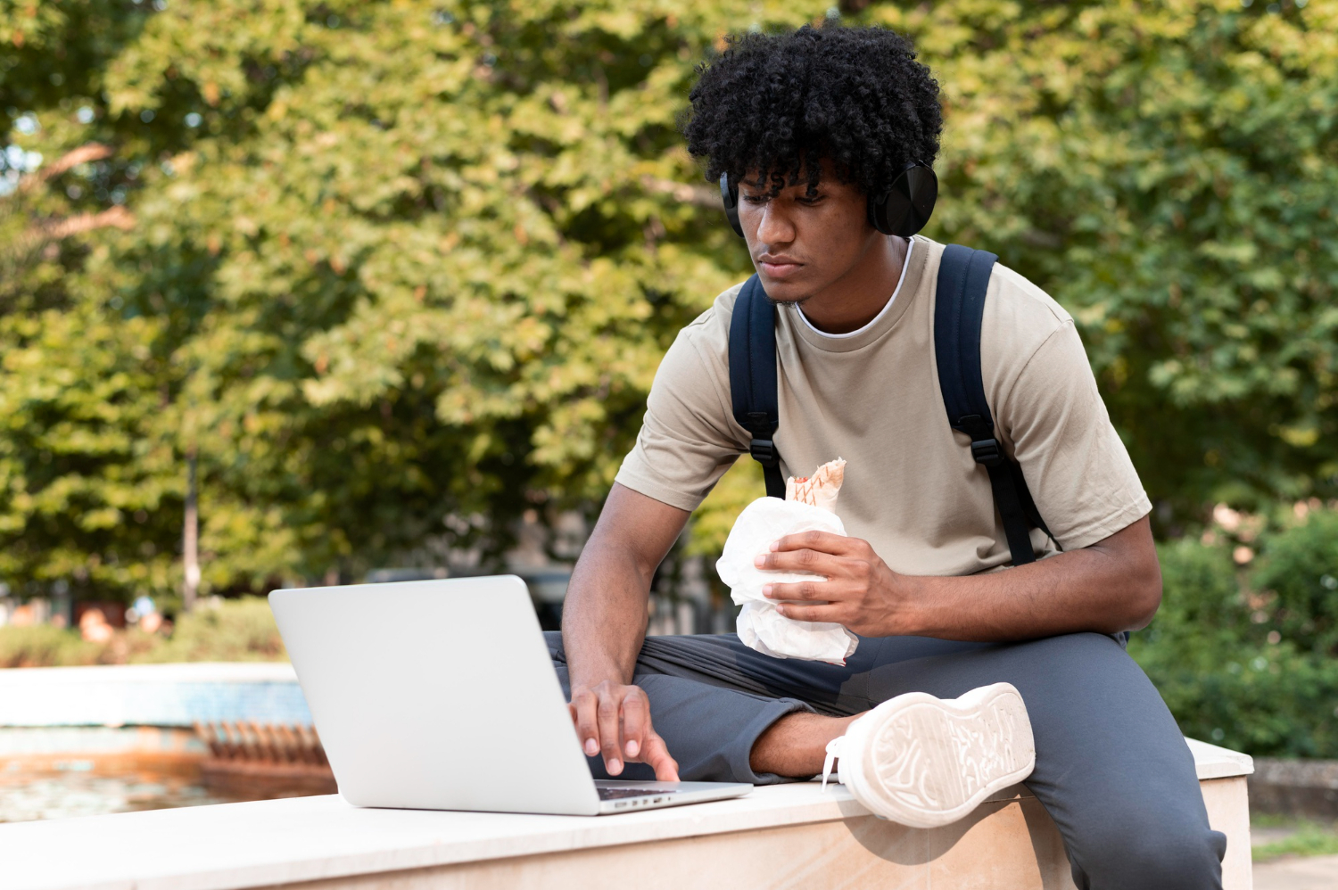 A diverse group of individuals sitting on a bench, engrossed in their laptops.