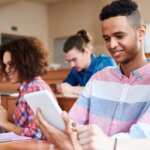 College students engage in the classroom using their devices.